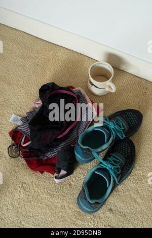 Leere Tasse und Frauenkleidung auf dem Schlafzimmerboden. Stockfoto