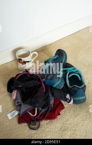 Leere Tasse und Frauenkleidung auf dem Schlafzimmerboden. Stockfoto