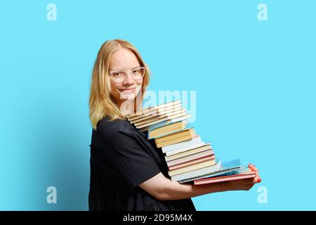 Studio Halblange Porträt eines fröhlichen kaukasischen Studenten mit einem großen Stapel von Büchern in seinen Händen.. Stockfoto