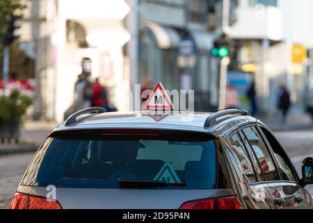 Auto mit lettischer Fahrschule Schild auf dem Dach, verschwommene Straße mit Ampel im Hintergrund Stockfoto