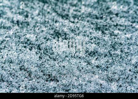 Schmelzender Schnee auf dem Autofenster. Nahaufnahme von Eiskristallen, die sich in Wasser verwandeln. Struktur der Kristalle. Stockfoto