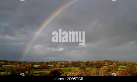 Ein Regenbogen erscheint über einem von Herbstfarben umgebenen Haus in der Nähe von Hawkhurst in Kent. Die Weidenhäuser sind ein besonderes Merkmal der Landschaft von Kent und Sussex und wurden ursprünglich zum Trocknen des geernteten reifen Hopfens gebaut, der als Zutat beim Bierbrauen verwendet wurde. Stockfoto