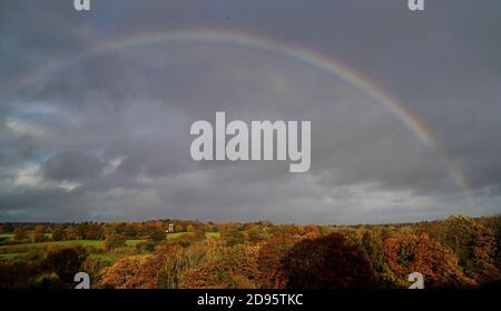 Ein Regenbogen erscheint über einem von Herbstfarben umgebenen Haus in der Nähe von Hawkhurst in Kent. Die Weidenhäuser sind ein besonderes Merkmal der Landschaft von Kent und Sussex und wurden ursprünglich zum Trocknen des geernteten reifen Hopfens gebaut, der als Zutat beim Bierbrauen verwendet wurde. Stockfoto