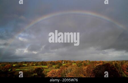 Ein Regenbogen erscheint über einem von Herbstfarben umgebenen Haus in der Nähe von Hawkhurst in Kent. Die Weidenhäuser sind ein besonderes Merkmal der Landschaft von Kent und Sussex und wurden ursprünglich zum Trocknen des geernteten reifen Hopfens gebaut, der als Zutat beim Bierbrauen verwendet wurde. Stockfoto