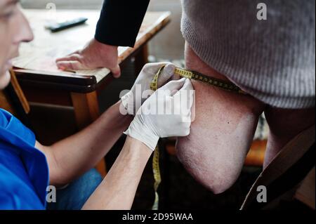 Der Prothesist entfernt das Maß von einer Person mit einer Behinderung, Frau mit Amputierte. Stockfoto