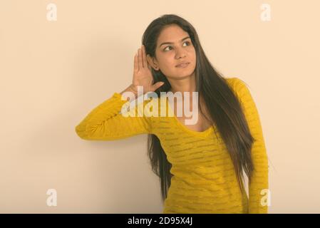 Studio shot der jungen indischen Frau denken, während gegen den weißen Hintergrund hören Stockfoto