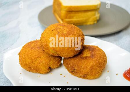 Drei Hähnchenbrotkuttchen übereinander mit Brotscheiben im Hintergrund Stockfoto