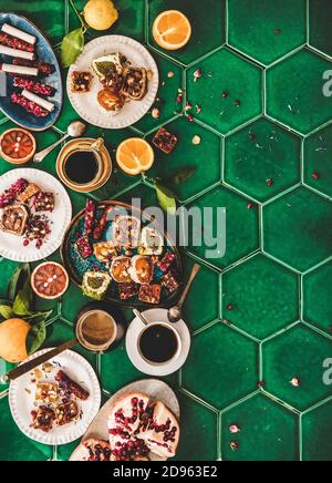 Flat-Lay der Vielfalt der türkischen traditionellen Lokum süße Freude mit türkischen Kaffee in Tassen und frische Früchte über grünen marokkanischen Fliesen Tisch, Draufsicht, Kopierraum. Nahöstliches typisches Dessertgericht Stockfoto