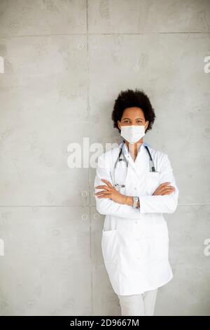 Weibliche afroamerikanische Arzt tragen weiße Uniform und schützende Gesichtsbehandlung Maske im Krankenhaus Stockfoto