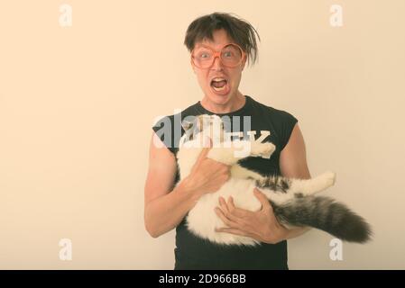 Studio shot Junger nerd Mann aufgeregt suchen, während Sie süße Katze und das Tragen von Brillen vor weißem Hintergrund Stockfoto