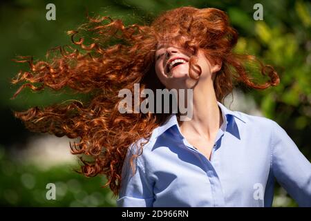 Nette junge Frau mit strömenden Haaren lacht über die Kamera Stockfoto