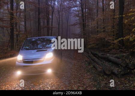 Camper van in wunderschönen Herbstwald mit Herbstlaub Blätter auf der Straße.Road trip und Reise Freiheit Konzept, Tourismus in RV (Freizeitfahrzeug). Stockfoto