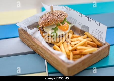 Nahaufnahme von Rindfleisch Burger auf Holztisch Hintergrund. Hamburger gegrillter Fleischburger, Salat, Tomaten und Spiegelei. Handgemachter Gourmet-Burger Stockfoto