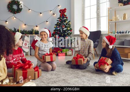 Gruppe von Kindern Freunde sitzen auf dem Boden in einem Kreis und sagen Grüße zu einander. Stockfoto