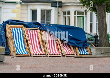 Eine Reihe von traditionellen Liegestühlen bereit für den Einsatz auf der Promenade in Llandudno, Wales gestapelt Stockfoto