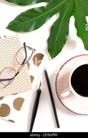 Sommerliche Komposition mit grünem Blatt, Tasse Kaffee, Brillen und Papeterie Stockfoto