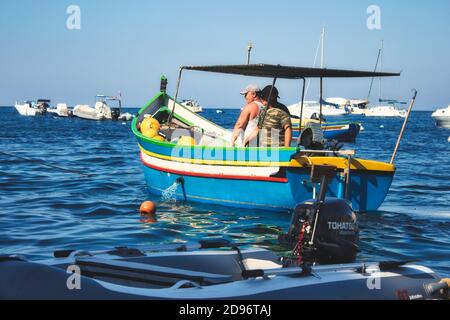 Gozo / Malta - Juli 27 2019: 2 Männer in einem bunten maltesischen Luzzu Fischerboot Stockfoto