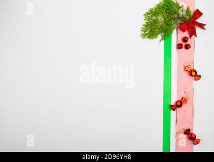 Weihnachtsdekorationen vertikal auf der Seite des Bildes mit Kopierraum auf weißem Hintergrund platziert, Kiefernzweige, Band, Bogen, Süßigkeiten. Stockfoto