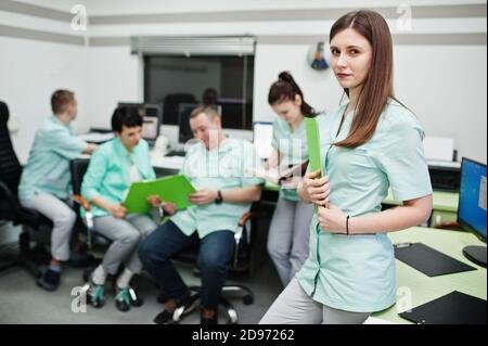 Medizinisches Thema .Porträt der weiblichen Ärztin mit Zwischenablage gegen Gruppe von Ärzten Treffen in der mrt-Büro im diagnostischen Zentrum im Krankenhaus. Stockfoto