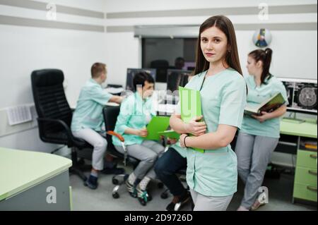 Medizinisches Thema .Porträt der weiblichen Ärztin mit Zwischenablage gegen Gruppe von Ärzten Treffen in der mrt-Büro im diagnostischen Zentrum im Krankenhaus. Stockfoto