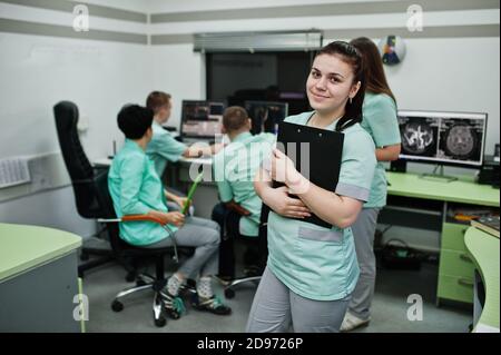 Medizinisches Thema .Porträt der weiblichen Ärztin mit Zwischenablage gegen Gruppe von Ärzten Treffen in der mrt-Büro im diagnostischen Zentrum im Krankenhaus. Stockfoto