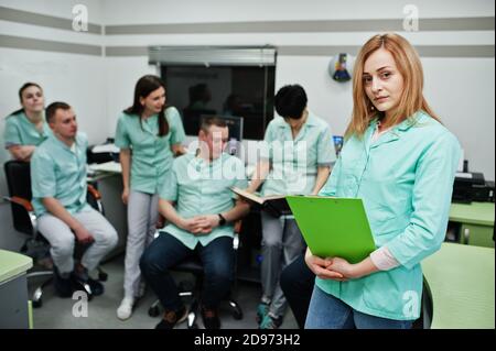 Medizinisches Thema .Porträt der weiblichen Ärztin mit Zwischenablage gegen Gruppe von Ärzten Treffen in der mrt-Büro im diagnostischen Zentrum im Krankenhaus. Stockfoto