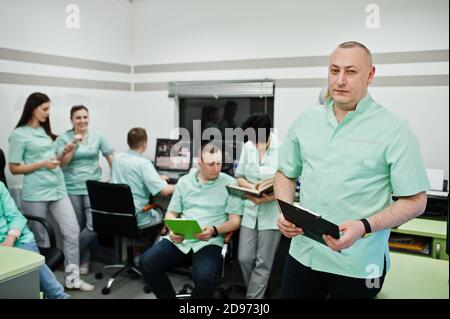 Medizinisches Thema .Porträt des Arztes mit Zwischenablage gegen Gruppe von Ärzten Treffen im mrt-Büro im Diagnostikzentrum im Krankenhaus. Stockfoto
