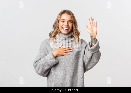 Bild von glücklichen ehrlichen Mädchen einen Arm heben und Hand auf Herz legen, Versprechen, schwören und Wahrheit sagen, stehen über weißem Hintergrund Stockfoto