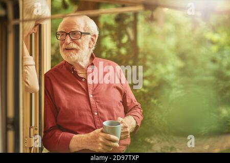 Taille von lächelnden grauhaarigen Mann im Gespräch mit seiner Frau in der Nähe des Eingangs zu ihrem Wohnmobil, während Kaffee halten. Reisekonzept. Speicherplatz kopieren Stockfoto