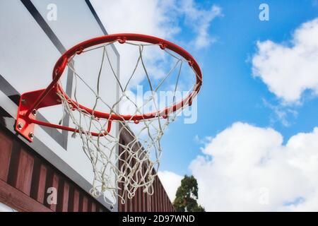 Basketballkorb mit Netz von unten mit blauem Himmel Hintergrund Stockfoto