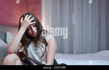 Teenager Mädchen leidet unter schweren Kopfschmerzen und findet sich im Bett in ihrem Zimmer liegen. Stockfoto