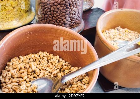 Keramikschalen und Glasgläser mit verschiedenen Cerealien zum Frühstück Stockfoto