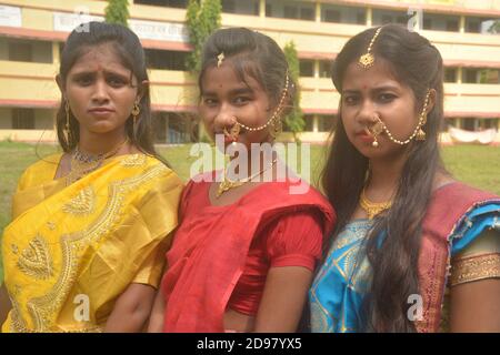 Drei Teenager Bengali Mädchen tragen Saree und Schmuck wie Nasenringe Ohrringe Halskette maang tika mit langen schwarzen Haaren, selektive Fokussierung Stockfoto