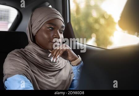 Geschäftstransfers. Selbstbewusst Schwarz Muslimische Geschäftsfrau Genießen Reiten Auto Auf Dem Rücksitz Stockfoto