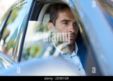 Junger Mann, der in diesem Auto in der Stadt sitzt Stockfoto