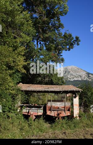 Alte oder Vintage landwirtschaftliche Anhänger gelagert unter Ramshackle Shelter, Car Shed, Carport, Scheune, Remise oder Bauernhof Nebengebäude Blieux Provence Frankreich Stockfoto