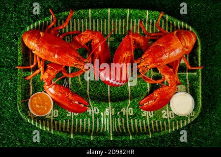 Zwei verzehrfertige Hummer mit Ball und Dipping Sauce auf grünen Teller. Abendessen mit Fußballparty. Stockfoto