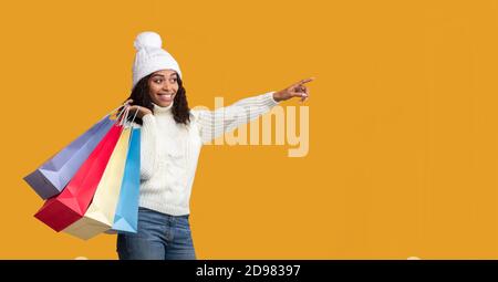 Schwarze Frau mit Einkaufstaschen, die auf freien Platz zeigen Stockfoto