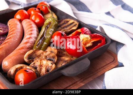 Gegrilltes Gemüse mit Würstchen, Tomaten, Paprika und Pilzen auf dem Grill Stockfoto