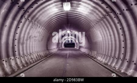 Großer Industriestile beleuchteter Tunnel mit Schatten an den Wänden. Weitwinkelansicht, ein-Punkt-Perspektive Stockfoto