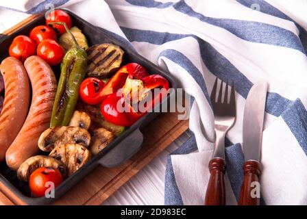 Gegrilltes Gemüse mit Würstchen, Tomaten, Paprika und Pilzen auf dem Grill Stockfoto