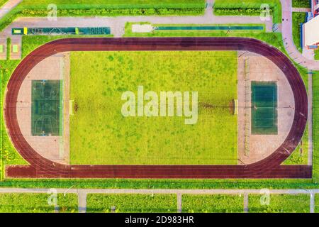 Kleines Stadion mit Laufstrecke, Fußballplatz, Basketballplatz und Tennisplatz. Luftaufnahme von oben Stockfoto