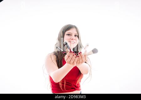 Teenager-Mädchen zeigt uns ihre Produkte besser zu machen. Sie zeigt uns ihre Pinsel, Lippenglossen und Lippenstifte. Stockfoto