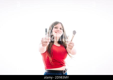 Teenager-Mädchen zeigt uns ihre Produkte besser zu machen. Sie zeigt uns ihre Pinsel, Lippenglossen und Lippenstifte. Stockfoto