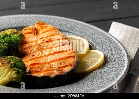 Gegrilltes Lachssteak mit Brokkoli auf grauem Teller Stockfoto