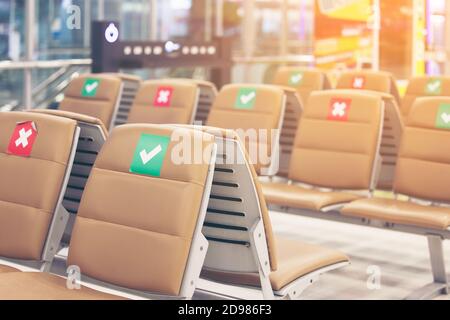 Symbol Aufkleber auf Stuhl im internationalen Flughafen. Neue normale und soziale Distanzierungskonzepte, Schutz Coronavirus-Infektion (Covid-19) Stockfoto