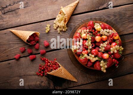 Biskuitkuchen mit verschiedenen Sommerfrüchten und Himbeeren auf Holz Tabelle Stockfoto