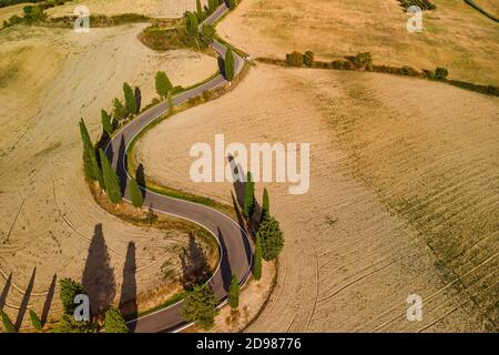 Malerische kurvenreiche Straße zwischen Getreidefeldern in der Nähe von Pienza Toskana Italien. Weitwinkelansicht. Drohne erschossen. Stockfoto