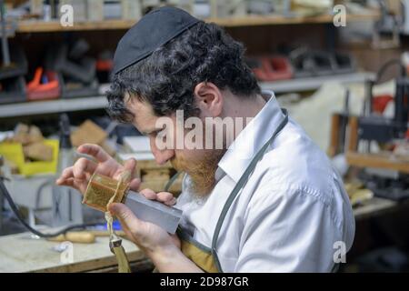 In seiner Werkstatt stellt ein Rabbiner und Handwerker Phylakterien (Tefillin) her, die von orthodoxen Juden während des Morgengebets verwendet werden. In Brooklyn, New York. Stockfoto