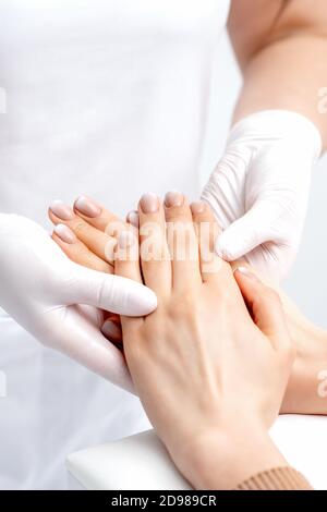Manikurist trägt Handschuhe dabei Wachs Massage auf weiblichen Händen mit Maniküre im Nagelstudio Stockfoto